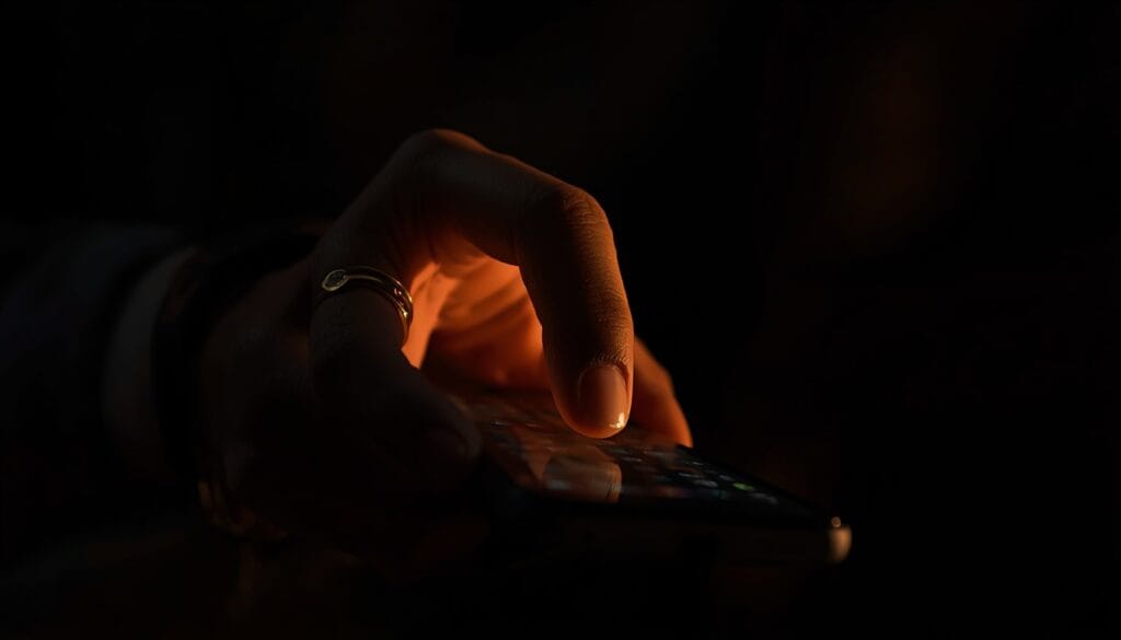 Primer plano de una mano dudando sobre el teléfono antes de escribir una respuesta, luz cálida tenue — respuesta fawn complacencia Mente Serena
